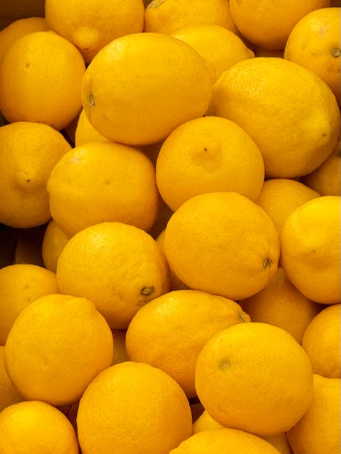 A close-up image of numerous fresh, ripe lemons with vibrant yellow skin, piled together to fill the frame. The lemons have a smooth surface with some minor blemishes and tiny nicks, and are lit evenly to highlight their bright color. The setting appears to be on a wooden surface, possibly in a kitchen or market display, though the background is not visible. The overall appearance emphasizes the fresh, clean, and appealing nature of the lemons, suitable for content related to food, freshness, or produce. No cleaning tools or surfaces are visible in this image. Carpet Cleaners Maida Vale does not appear in the image but is associated with general cleaning content for residence or commercial spaces.